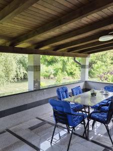 a patio with a glass table and blue chairs at Apartmani Lucica in Jajce