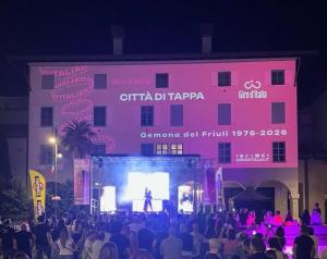 a crowd of people standing in front of a pink building at LA MUELE Affittacamere in Gemona del Friuli