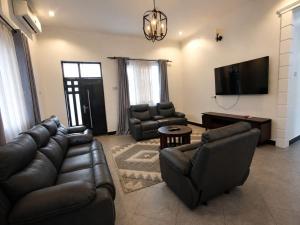 a living room with leather furniture and a flat screen tv at Boma Retreat in Boma la Ngombe