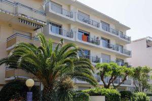 an apartment building with palm trees in front of it at Studio à 50 m de la plage in Arcachon
