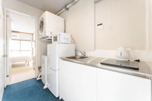 a white kitchen with a sink and a refrigerator at Maison Atago201 in Fukuoka