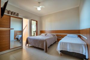 a bedroom with two beds and a mirror at Souza Apart 1 - Apartamentos completos com muito aconchego in São Thomé das Letras