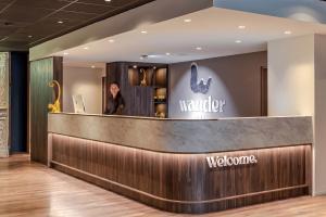 a man standing behind a counter in a lobby at Hotel Wander in Wageningen