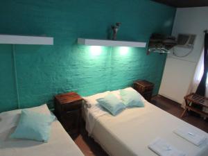 two beds in a room with a green wall at YPORA Ldg in Colonia Carlos Pellegrini