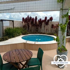 a swimming pool with a table and a table and chairs at Apt Completo com Vista para o Mar, Ar Condicionado e Café da Manhã Opcional in Recife