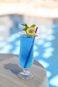 Ein blaues Getränk steht auf einem Tisch neben einem Pool. in der Unterkunft Senator Hotel Apartments - Adults Only in Ayia Napa