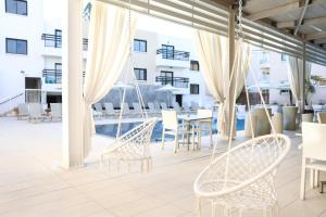 eine Terrasse mit Stühlen und Tischen und ein Pool in der Unterkunft Senator Hotel Apartments - Adults Only in Ayia Napa