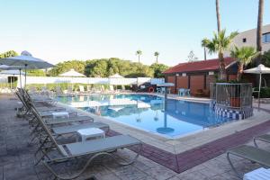 ein großer Swimmingpool mit Liegestühlen und Sonnenschirmen in der Unterkunft Senator Hotel Apartments - Adults Only in Ayia Napa