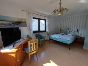 a bedroom with a bed and a desk with a television at Adelheids Apartment in Lützelbach