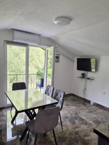 a dining room with a table and chairs and a television at Apartmani Lucica in Jajce