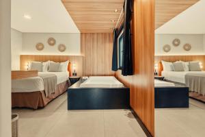 a hotel room with two beds and a bathtub at Pousada Antonella in Morro de São Paulo