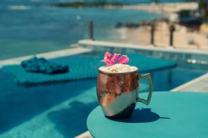 a coffee cup sitting on a table next to a pool at Pousada Antonella in Morro de São Paulo