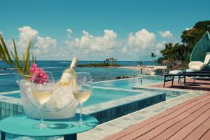 a table with a bottle of wine and glasses next to a swimming pool at Pousada Antonella in Morro de São Paulo