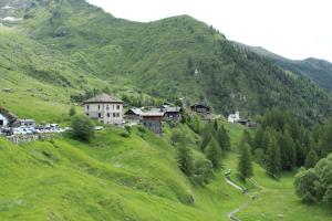 a village on a green hill with a mountain at Albergo Alpino Cheggio in Alpe Cheggio