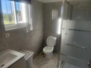 a bathroom with a toilet and a sink and a window at House Proença in Ladoeiro
