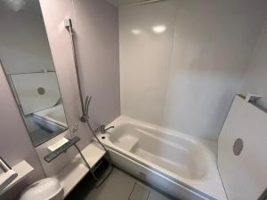 a white bathroom with a tub and a toilet at Lemon みやざき in Miyazaki