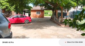 a red car parked in a parking lot at Peach City Hotel in Prampram