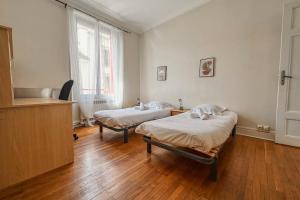 two beds in a room with wooden floors at #EU L'Authentique in Grenoble