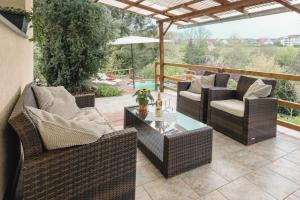 Eine Terrasse mit Korbstühlen, einem Tisch und einem Sonnenschirm in der Unterkunft WEINQUARTIER Kalter Hügel 70 qm Garten Lagerfeuer Pool Terrasse Parkplatz in Naumburg