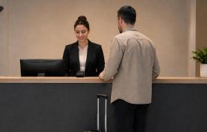 Ein Mann und eine Frau schütteln sich an einem Tresen die Hände. in der Unterkunft Hotel Miano by Limehome in München