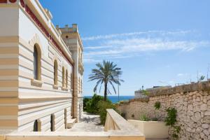 サンタ・チェザーレア・テルメにあるVilla Raffaellaのヤシの木と海を背景にした建物