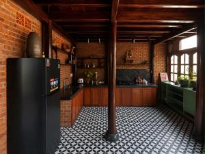 a kitchen with a black refrigerator and a brick wall at Wooden chill house in Hoi An