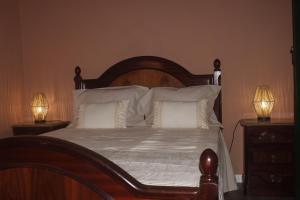 a bedroom with a bed with white pillows and two lamps at Casa Velha in Mourão