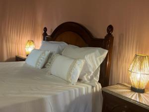 a bed with white sheets and pillows next to two lamps at Casa Velha in Mourão