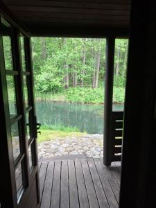 an open door to a porch with a view of a lake at Forest House in Pašvinės +4 photos