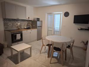 a kitchen with a table and a table and chairs at Apartmani T'n'T in Pag