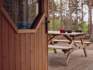 a picnic table on a deck in the woods at Chalet Beekeepers Bothy by Interhome in Coldstone +8 photos