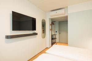 a bedroom with a flat screen tv on the wall at Fred Hotel Central in Zurich