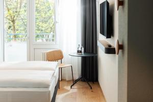 a bedroom with two beds and a table and a window at Fred Hotel Central in Zurich +16 photos