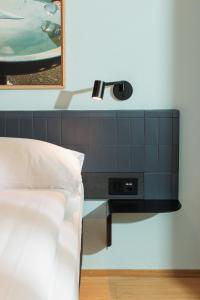 a bedroom with a bed and a lamp on a wall at Fred Hotel Central in Zurich
