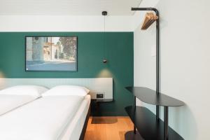 a bedroom with a white bed and a green wall at Fred Hotel Central in Zurich