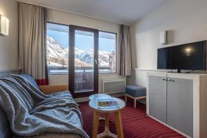 a hotel room with a couch and a tv and a table at Résidence Pierre & Vacances La Daille in Val-d'Isère