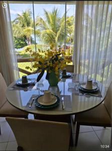 a dining room table with a vase of flowers on it at Paraíso dos corais Pe na areia in Guarajuba