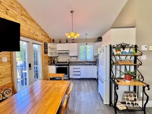 a kitchen with a wooden table and a refrigerator at Chalet au bord du lac à la Baie Boudreault in Alma