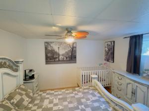 a baby room with a crib and a ceiling fan at Chalet au bord du lac à la Baie Boudreault in Alma