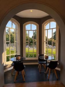 two tables and chairs in a room with windows at La Olivia Hotel Boutique & Spa in La Falda