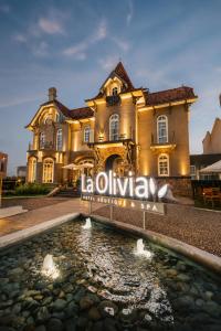 a building with a sign in front of a pond at La Olivia Hotel Boutique & Spa in La Falda
