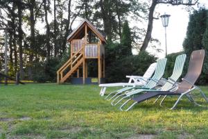 two lawn chairs sitting in the grass in front of a play house at Ferienhof Tödter in Schneverdingen