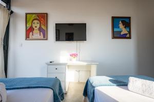 a bedroom with two beds and a desk and a painting at Casa Arte by Vibrant in Vichayito
