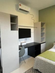 a bedroom with a bed and a desk with a television at Studio Inap Seri Iskandar in Kampong Bota Road