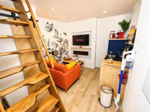 a living room with a staircase and a orange chair at MRODBNB - Maisonnette Atypique enfouie dans la Roche - Gr34, Plage, Resto & Huîtres à 25m in Cancale