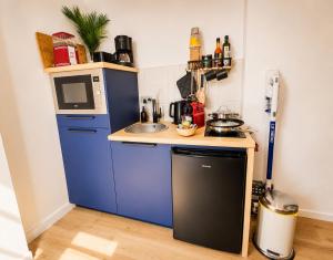 a small kitchen with a blue refrigerator and a sink at MRODBNB - Maisonnette Atypique enfouie dans la Roche - Gr34, Plage, Resto & Huîtres à 25m in Cancale +10 photos