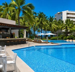 a pool at a resort with chairs and umbrellas at Luxury Beachfront Condo at Krystal Grand Resort - NEWLY REMODELED & NEWLY FURNISHED in Bucerías