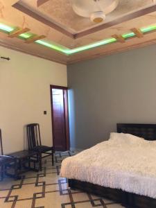 a bedroom with a bed and a chair and a ceiling at Cozy Corner Two-Bedroom in Abbottabad