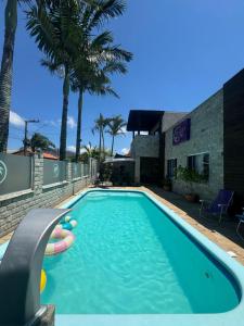 a swimming pool with a persons hand in front of a building at Suíte Maresia - Pousada Castelo do Luar in Penha