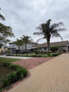 a brick walkway with palm trees in front of a building at Crocus Corner - Kyalami in Kyalami